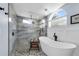 Bright bathroom showcasing a modern tub, arched window, and sleek glass enclosed shower at 14867 Bonnybridge Dr, Orlando, FL 32826