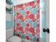 Bathroom with a colorful floral shower curtain, toilet, storage rack, and a white door at 14867 Bonnybridge Dr, Orlando, FL 32826