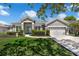 Charming gray home featuring a well-manicured lawn, lush landscaping, and a two-car garage at 14867 Bonnybridge Dr, Orlando, FL 32826