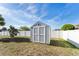 A gray storage shed stands in the backyard against a white fence, providing practical outdoor storage at 9945 Sw 55Th Avenue Rd, Ocala, FL 34476