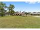 Expansive front lawn leading to a charming single-story home with mature landscaping and a red front door at 10458 Sw 52Nd Ct, Ocala, FL 34476