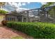 Back exterior view of a screened-in pool with covered patios and trimmed shrubs at 1882 Royal Lytham Ct, Port Orange, FL 32128