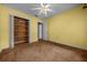 Bedroom featuring yellow walls and carpeting, with closet and adjoining room, and ceiling fan with light at 2030 Se 32Nd Ln, Ocala, FL 34471