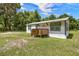 Exterior view of a quaint single-story home with a wooden porch and fresh paint, surrounded by lush greenery at 21776 Nw 57Th Ave, Micanopy, FL 32667