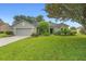 Charming one-story home featuring a well-manicured lawn, lush landscaping, and a two-car garage at 23510 Oak Prairie Cir, Sorrento, FL 32776