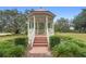 Beautifully landscaped gazebo with stairs and surrounding shrubbery on a sunny day at 23510 Oak Prairie Cir, Sorrento, FL 32776
