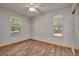 An empty bedroom with wood floors, neutral walls, and natural light from two windows at 3005 Se 156Th Place Rd, Summerfield, FL 34491