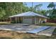 View of the home's exterior showcasing the long driveway, white metal roof, and landscaping around the front entryway at 3005 Se 156Th Place Rd, Summerfield, FL 34491