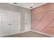Bright bedroom with a pink accent wall featuring a geometric design, complemented by two closet doors at 1157 Hollow Pine Dr, Oviedo, FL 32765
