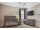 Charming Bedroom featuring a gray crib, dresser, and mounted TV, creating a cozy and modern space at 1157 Hollow Pine Dr, Oviedo, FL 32765
