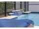 Lovely waterfall feature in a screened-in pool with blue tile accents at 1157 Hollow Pine Dr, Oviedo, FL 32765
