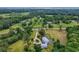 A stunning aerial view of the home, driveway and manicured yard, and surrounding trees at 20250 Nw 71St Ct, Micanopy, FL 32667