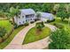 Aerial view showcasing the home and detached garage, surrounded by a large driveway and mature trees at 20250 Nw 71St Ct, Micanopy, FL 32667