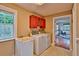 Neutral laundry room with washer, dryer, wash basin, and red cabinets, with sightlines to the rest of the house at 20250 Nw 71St Ct, Micanopy, FL 32667