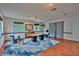 Spacious living room featuring wood floors, an area rug, a comfortable chair, and light from two windows at 20250 Nw 71St Ct, Micanopy, FL 32667