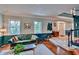 Inviting living room with a green velvet couch, hardwood floors, and bright windows at 20250 Nw 71St Ct, Micanopy, FL 32667