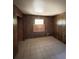 Empty bedroom with wood paneling, tile floors, and a boarded window at 15750 Ne 150Th Ter, Fort Mc Coy, FL 32134