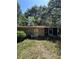 Exterior view of a stone sided home with lush, mature trees, greenery and overgrown lawn at 15750 Ne 150Th Ter, Fort Mc Coy, FL 32134