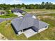 Aerial view of a gray house with a paver patio on a green lawn overlooking a golf course at 17781 Sw 72Nd Street Rd, Dunnellon, FL 34432