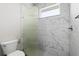 Modern bathroom with white marble-style tiled walls and glass shower enclosure at 17781 Sw 72Nd Street Rd, Dunnellon, FL 34432