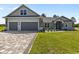 Beautiful home featuring a gray exterior, two-car garage, brick paved driveway, and lush green lawn at 17781 Sw 72Nd Street Rd, Dunnellon, FL 34432