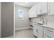 Well-lit laundry room with white cabinetry, a sink, and a large window at 17781 Sw 72Nd Street Rd, Dunnellon, FL 34432
