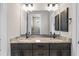 Elegant bathroom featuring double sinks with granite countertops, spacious mirror, and dark cabinets at 17887 Sw 72Nd Street Rd, Dunnellon, FL 34432