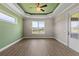Bedroom features a tray ceiling, ceiling fan, and windows overlooking the backyard at 17887 Sw 72Nd Street Rd, Dunnellon, FL 34432