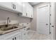 Bright laundry room features white cabinets, stone countertops, and modern fixtures at 17887 Sw 72Nd Street Rd, Dunnellon, FL 34432
