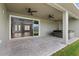 An outdoor patio with ceiling fans and sliding doors, overlooking a spacious backyard with a spa at 17887 Sw 72Nd Street Rd, Dunnellon, FL 34432