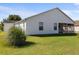 A view of the home's backyard and screened in patio with green grass and natural growth at 2297 Montbrook Pl, The Villages, FL 32162