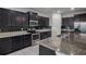 Modern kitchen with dark cabinetry, stainless steel appliances, and granite countertops at 4261 Sw 62Nd Loop, Ocala, FL 34474