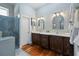 Bathroom with double vanity sinks, stylish lighting, walk-in shower and warm wood accents at 3943 Nw 219Th Street Rd, Micanopy, FL 32667
