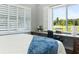 Bedroom featuring large bed, white shutters, view of outdoors and workstation desk at 3943 Nw 219Th Street Rd, Micanopy, FL 32667