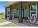 Inviting front porch with rocking chairs, brick accents, and views of the surrounding landscape at 3943 Nw 219Th Street Rd, Micanopy, FL 32667