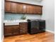 Laundry room featuring front load washer and dryer with dark wood cabinets and blue backsplash at 3943 Nw 219Th Street Rd, Micanopy, FL 32667
