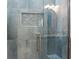 Glass enclosed shower featuring blue tiles, built-in seat, shampoo niche and chrome fixtures at 3943 Nw 219Th Street Rd, Micanopy, FL 32667