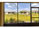 A screened-in lanai offers a serene view of the backyard, showcasing lush green grass and neat landscaping at 8925 Sw 76Th St, Ocala, FL 34481