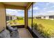 A screened-in lanai offers a serene view of the backyard, showcasing lush green grass and neat landscaping at 8925 Sw 76Th St, Ocala, FL 34481