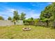 Landscaped backyard featuring a brick fire pit surrounded by lawn and fencing at 680 Nw 67Th Pl, Ocala, FL 34475