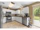 Bright kitchen with stainless steel appliances, granite countertops, and sliding glass doors to backyard at 680 Nw 67Th Pl, Ocala, FL 34475