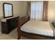 Bedroom with dresser, mirror, and wood sleigh bed next to window with patterned curtains for a bright and inviting space at 2233 Ardon Ave, Orlando, FL 32833