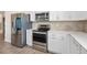 Modern kitchen boasts stainless steel appliances, white cabinetry, and stylish backsplash at 9478 Sw 52Nd Loop, Ocala, FL 34481