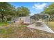 Exterior home view with carport, wood steps, gray siding, AC unit and mature trees at 221 Se 167Th Ct, Silver Springs, FL 34488
