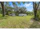 Exterior view of home with a carport and outbuilding set within a large, grassy yard with mature trees at 221 Se 167Th Ct, Silver Springs, FL 34488