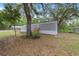 Exterior of home with mature trees, gray siding, carport and wood steps at 221 Se 167Th Ct, Silver Springs, FL 34488