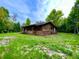 Charming cabin exterior with brick foundation, surrounded by a lush, green lawn and mature trees at 3682 Jack Pine Ln, Ormond Beach, FL 32174