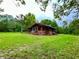 Quaint cabin exterior with brick accents, screened porch, and mature trees in a serene, natural setting at 3682 Jack Pine Ln, Ormond Beach, FL 32174