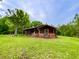 Rustic cabin exterior with brick foundation, charming front porch, and surrounded by lush greenery at 3682 Jack Pine Ln, Ormond Beach, FL 32174