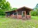 Cozy cabin with brick foundation, screened porch, and surrounded by a green lawn at 3682 Jack Pine Ln, Ormond Beach, FL 32174